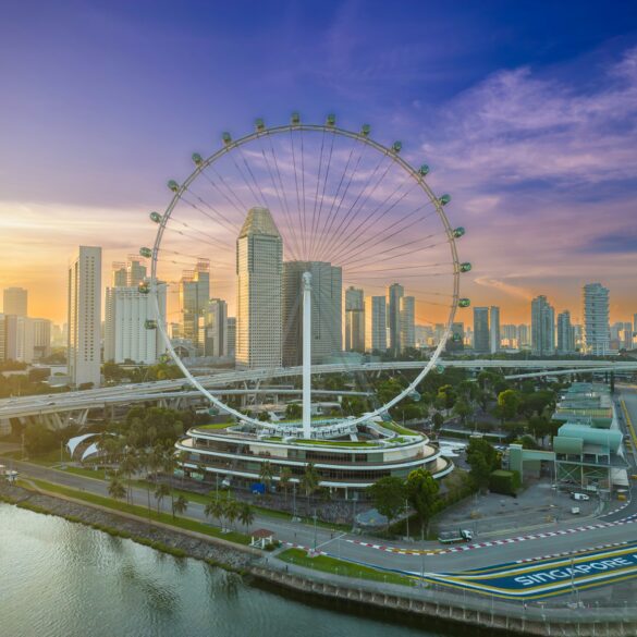 Aerial view of the Singapore Flyer and Marina Bay skyline at sunrise, with the Marina Bay Street Circuit track visible below