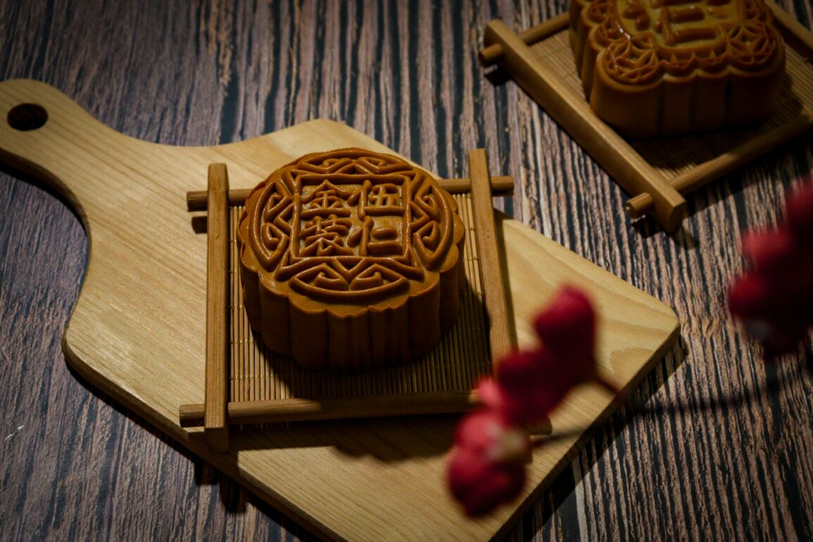 Intricately carved mooncake mould rests on a wooden cutting board, showcasing traditional Mid-Autumn Festival craftsmanship.