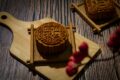 Intricately carved mooncake mould rests on a wooden cutting board, showcasing traditional Mid-Autumn Festival craftsmanship.