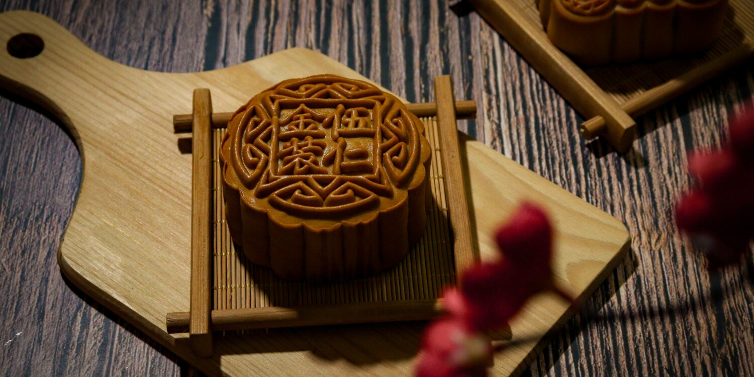 Intricately carved mooncake mould rests on a wooden cutting board, showcasing traditional Mid-Autumn Festival craftsmanship.