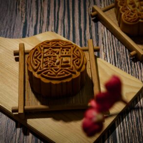 Intricately carved mooncake mould rests on a wooden cutting board, showcasing traditional Mid-Autumn Festival craftsmanship.