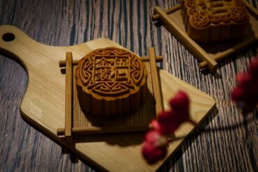 Intricately carved mooncake mould rests on a wooden cutting board, showcasing traditional Mid-Autumn Festival craftsmanship.