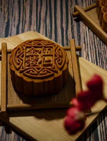Intricately carved mooncake mould rests on a wooden cutting board, showcasing traditional Mid-Autumn Festival craftsmanship.