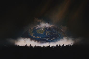 Silhouette of YE atop a glowing globe stage, with a crowd gathered below at YE Live in Jakarta 2026.