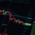 Cryptocurrency trading screen showing a candlestick price chart in a downward trend, with live price data displayed alongside.