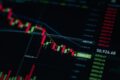 Cryptocurrency trading screen showing a candlestick price chart in a downward trend, with live price data displayed alongside.