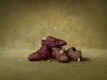 PUMA x ROSÉ Speedcat sneakers in burgundy and brown nubuck leather with wrapped laces, stacked on an olive green backdrop with white butterflies.