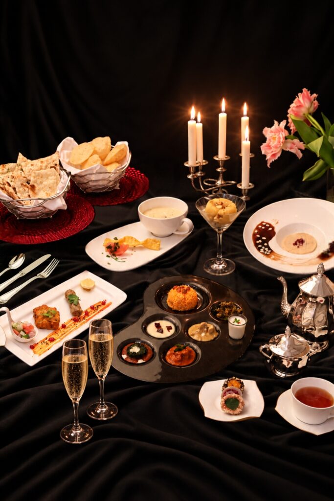 A Deepavali tasting menu at Amrith by The Song of India, Singapore, with a palette-shaped thali, kebabs, shorba, kulfi and bread baskets laid out on dark velvet beside lit candles.
