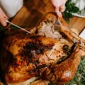 Hands carving a herb-crusted roast turkey for Christmas takeaways 2026 in Singapore