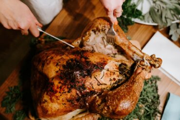 Hands carving a herb-crusted roast turkey for Christmas takeaways 2026 in Singapore