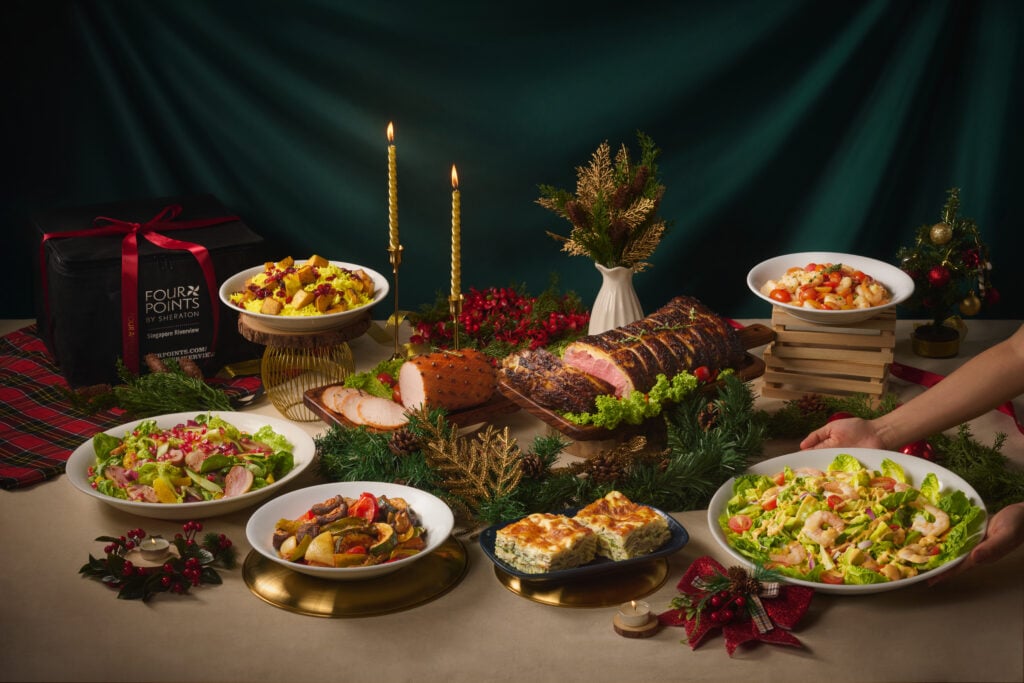Four Points by Sheraton Singapore, Riverview Christmas catering buffet with Honey-baked Ham, roast meats, salads and pasta beside a branded delivery bag