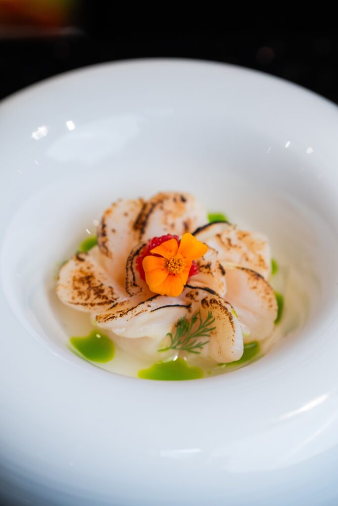 Torched Hokkaido scallops arranged in a ring with roe, herb oil and an orange flower at Ingleside on Tras Street.