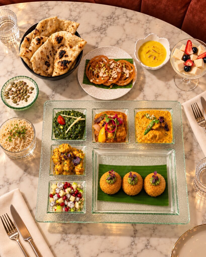 Rang Mahal’s Deepavali thali in Singapore, with palak cheese croquettes on banana leaf, kadai paneer, curries, jalebi, rabdi and naan arranged on a marble table.