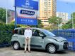 Tribecar co-founder Adrian Lee, standing beside a grey-green Tribecar car sharing MPV, in front of Tribecar and Popular Rent A Car by Tribecar signage in Singapore.