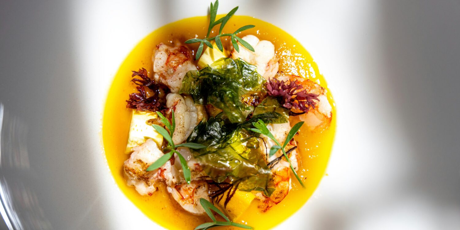 Seared langoustines with pineapple, crisp seaweed and fresh herbs in a golden yellow sauce, for new restaurants in Singapore September 2026.